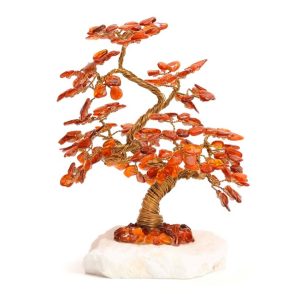 Arbre de vie en ambre posé sur une pierre blanche.