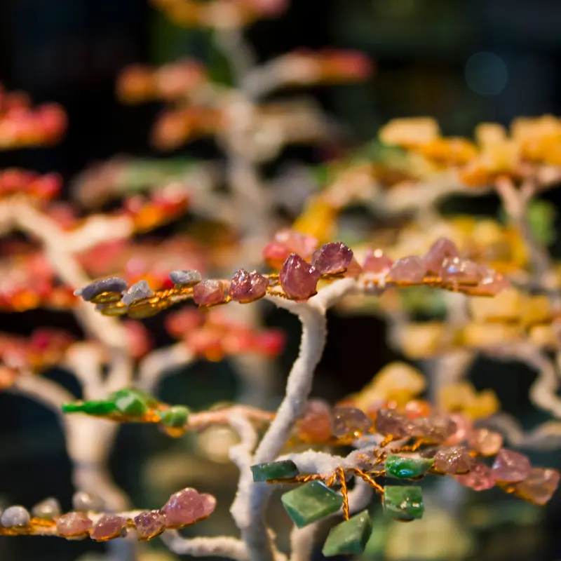 Les branches de plusieurs arbres de vie décoratifs en pierres naturelles rouges, jaunes et vertes.